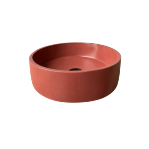 A round circular concrete basin medium in size in a stunning coral/burnt organe. Featuring a black waste plug on a plain white background.